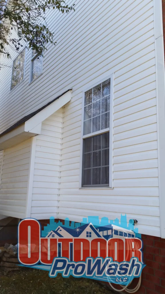 A white house with two windows and a blue sign.